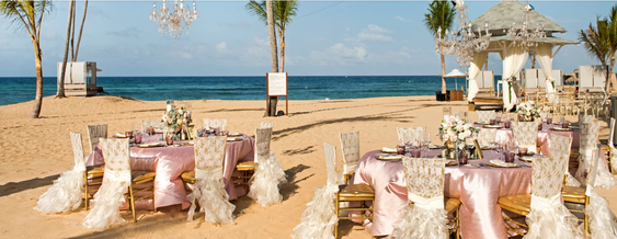 Wedding reception setup on a beach in front of the ocean.
