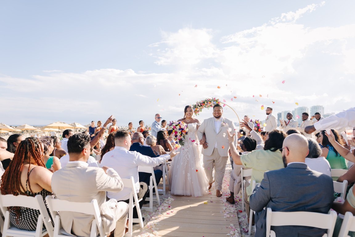 Newly married couple walking through their destination wedding guests