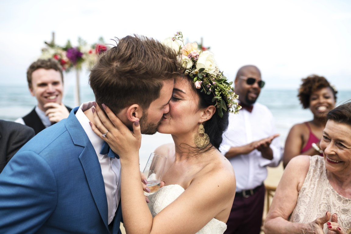 Bride and groom kissing during beach wedding celebration