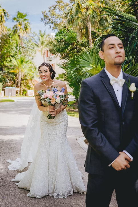 Bride smiling behind groom in an outdoor tropical wedding setting