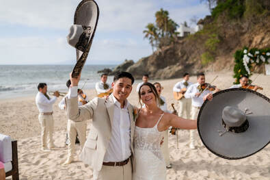Destination wedding couple celebrating on the beach with mariachi musicians