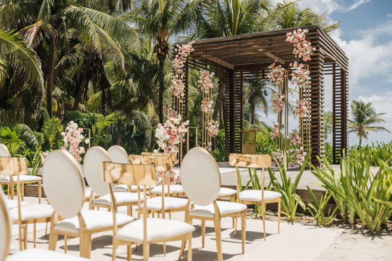 Tropical destination wedding ceremony setup with floral arch