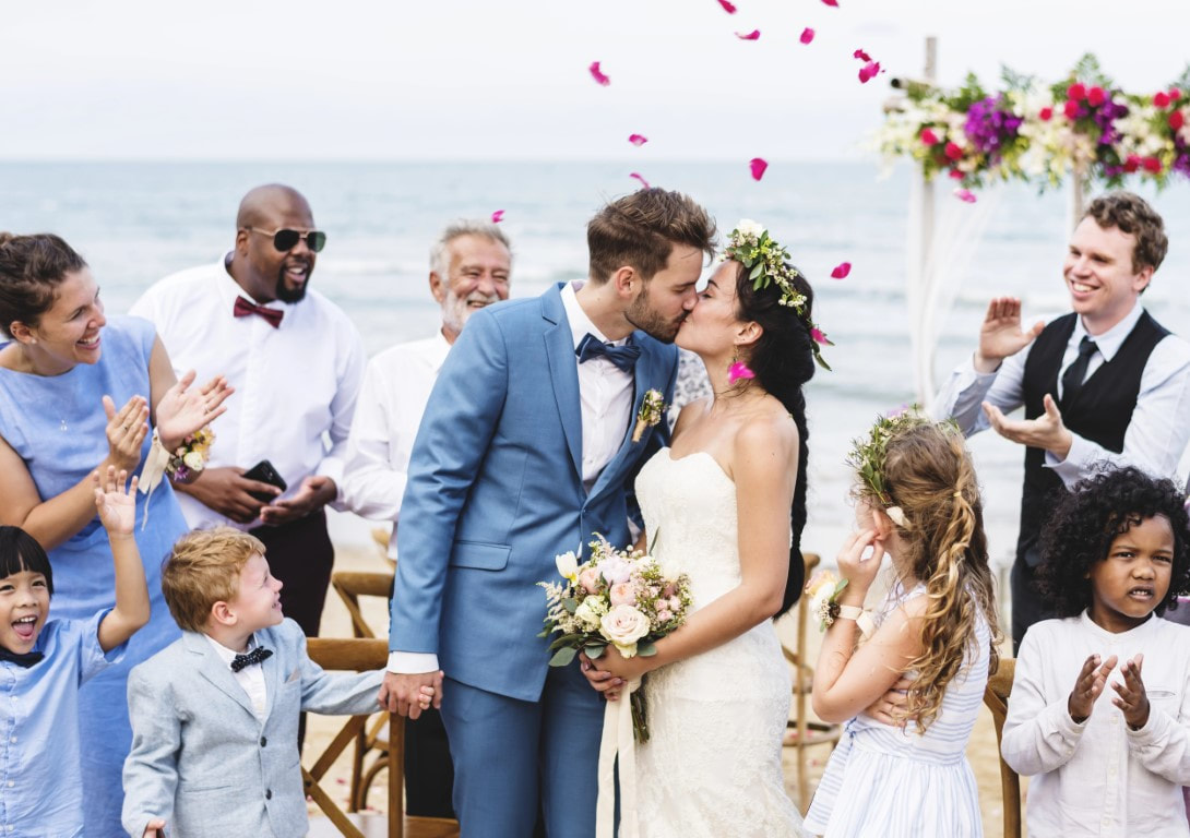Bride and groom celebrating with wedding guests on the beach